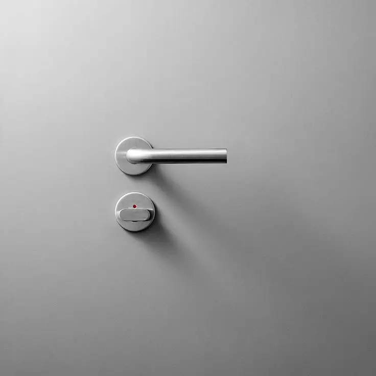 A sleek, minimalist chrome handle on a modern grey door.
