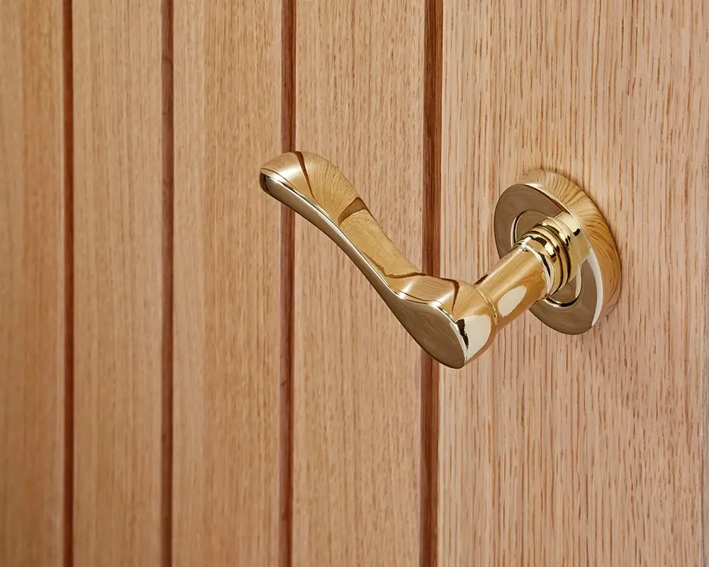 A craftsman carefully polishing a brass door handle.