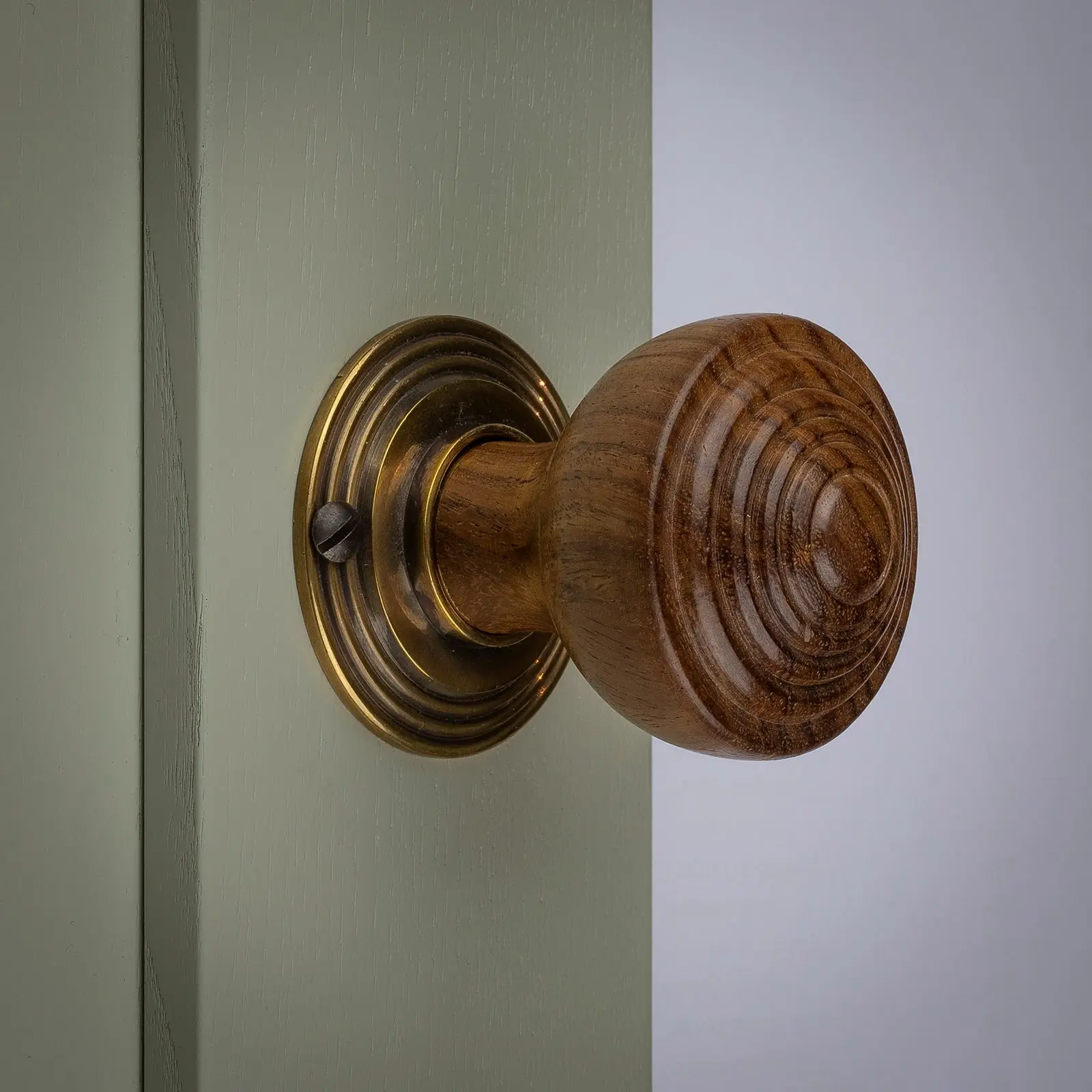 Close-up of a classic brass knob on a dark wooden door.